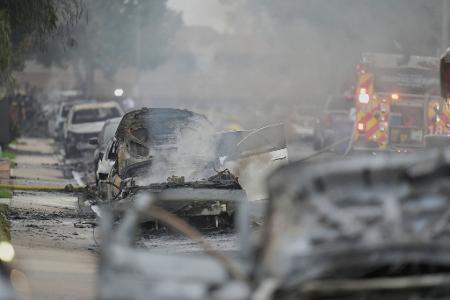 Einsatzkräfte fahren an beschädigten Fahrzeugen am Schauplatz des Absturzes eines Kleinflugzeugs in einem Stadtviertel von San Diego vorbei. 