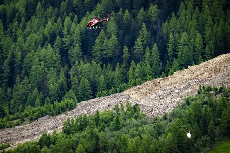 Ein Helikopter der Air Zermatt fliegt über einer Alp.