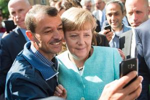 Bald zehn Jahre her: Angela Merkel (CDU) lässt sich nach dem Besuch einer Erstaufnahmeeinrichtung für Asylbewerber in Berlin-Spandau für ein Selfie zusammen mit einem Flüchtling fotografieren. (Archivbild)