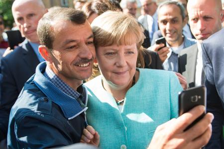 Bald zehn Jahre her: Angela Merkel (CDU) lässt sich nach dem Besuch einer Erstaufnahmeeinrichtung für Asylbewerber in Berlin-Spandau für ein Selfie zusammen mit einem Flüchtling fotografieren. (Archivbild)