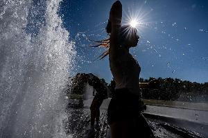 Temperaturen von annähernd 40 Grad in der Hauptstadt - diese Touristen nutzen einen Brunnen zur Abkühlung.