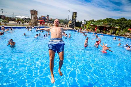 Niklas H.aus Heideburg in Rheinland-Pfalz springt bei sommerlichen Temperaturen rückwärts in den großen Pool auf dem Festivalgelände.