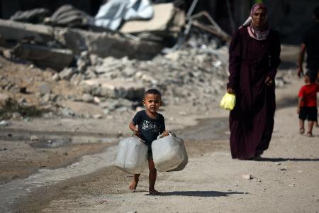 Ein Kind trägt Kanister, während Palästinenser versuchen, ihren täglichen Wasserbedarf zu decken, indem sie Kanister aus Wassertankwagen füllen, die in das Gebiet in Gaza-Stadt gebracht wurden.
