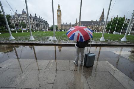Wetter in Großbritannien: Ein Passant trägt einen Regenschirm auf dem Parliament Square in Westminster im Zentrum Londons. 