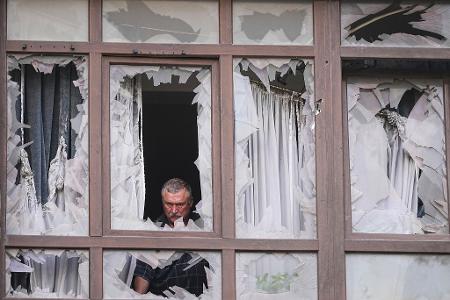 Ukraine-Krieg - Mann inspiziert zerstörtes Haus