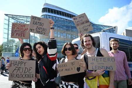 Teilnehmerinnen und Teilnehmer greifen auf ihren Plakaten auch die Kontroverse um die Regenbogenflagge am Bundestag auf.